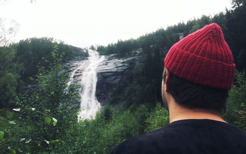 A man wearing a Red Cap, watching a waterfall.